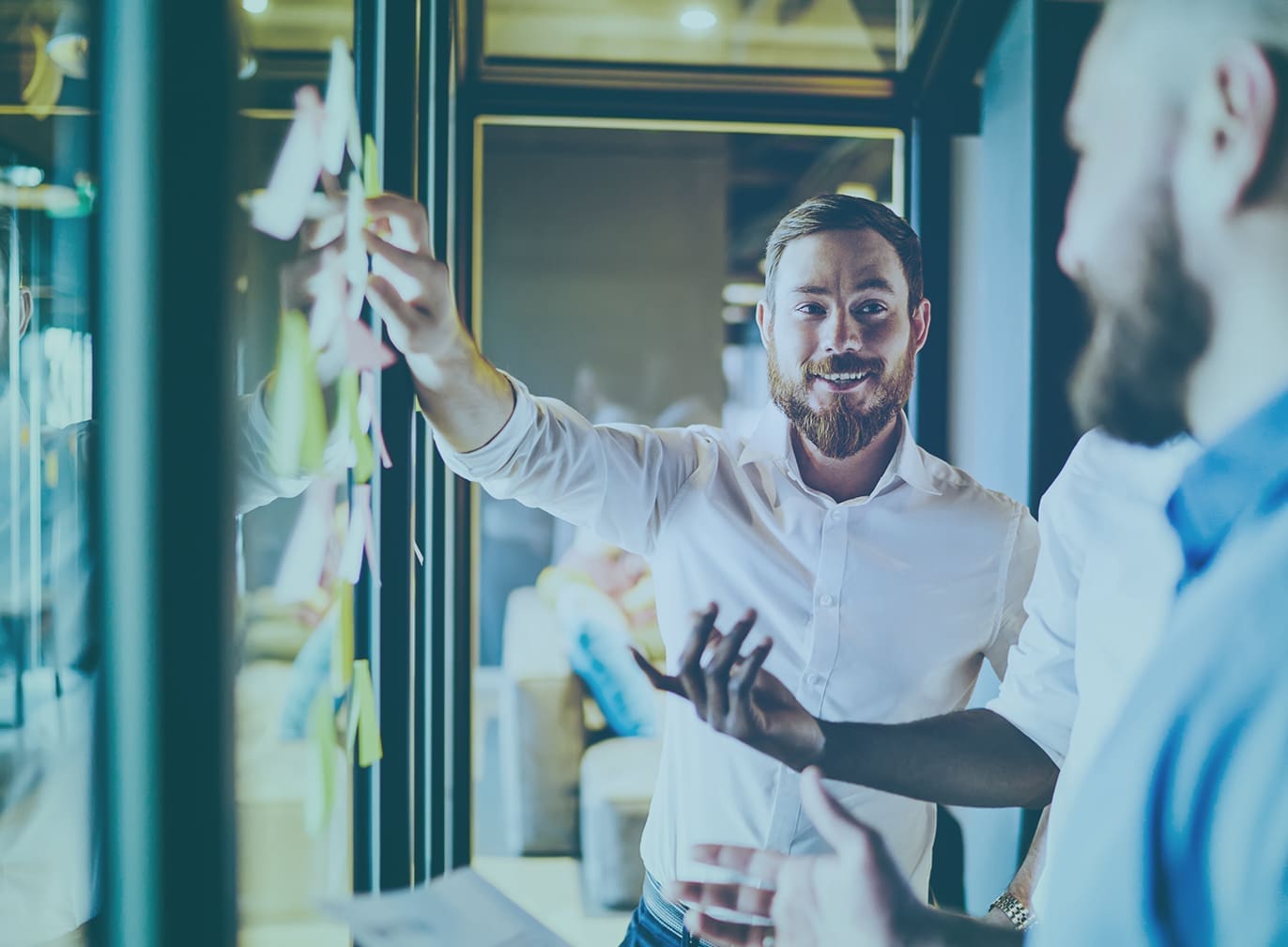 Leadership team collaborating at a glass wall covered in sticky notes during a strategy session
